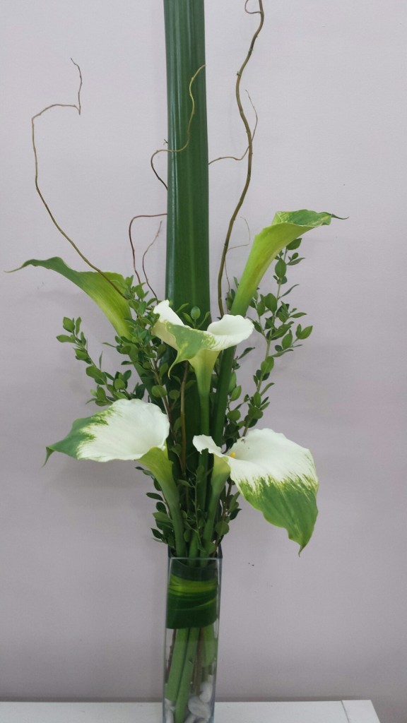 Green goddess lilies in a glass vase with willow