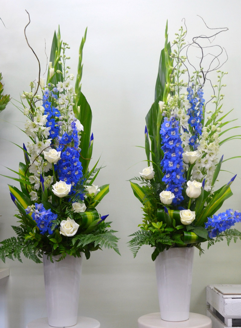 Pedestal arranegment with white and blue flowers and tropical leaves