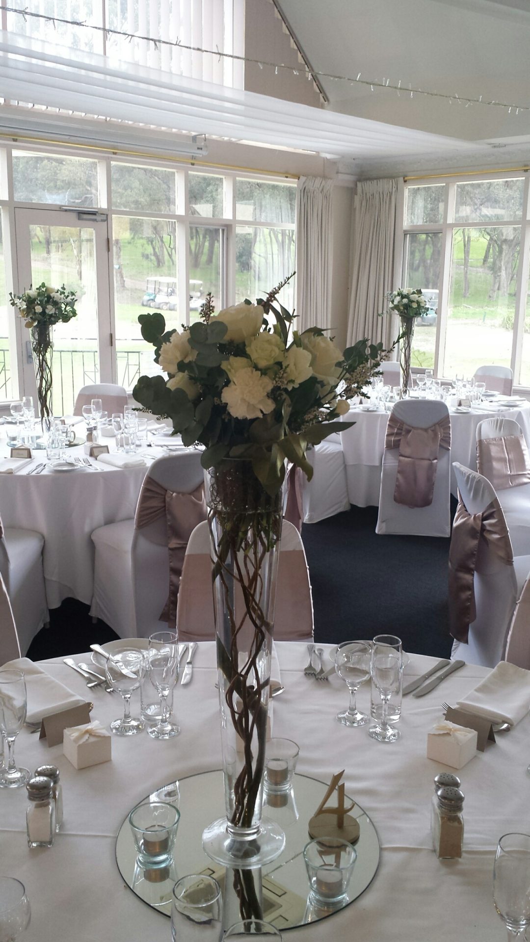 tall glass vases with willow inside and white posy ontop